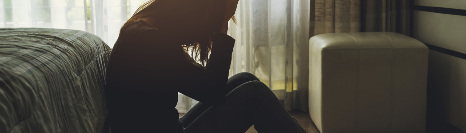 depressed woman sitting in the dark bedroom